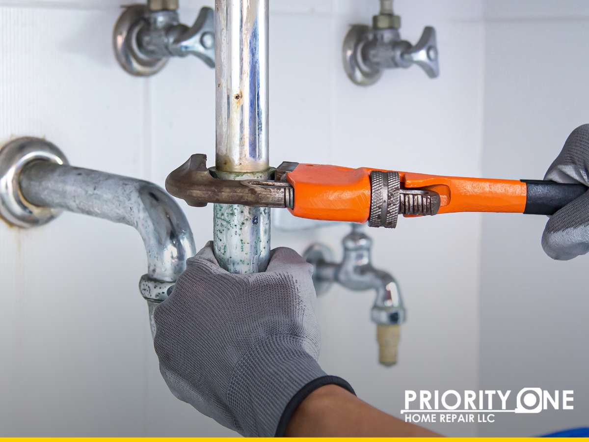 Plumber using an orange wrench to repair water damage leaks in a home's piping system